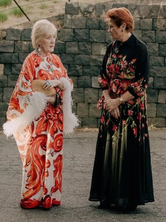 Two woman speaking in long dresses.