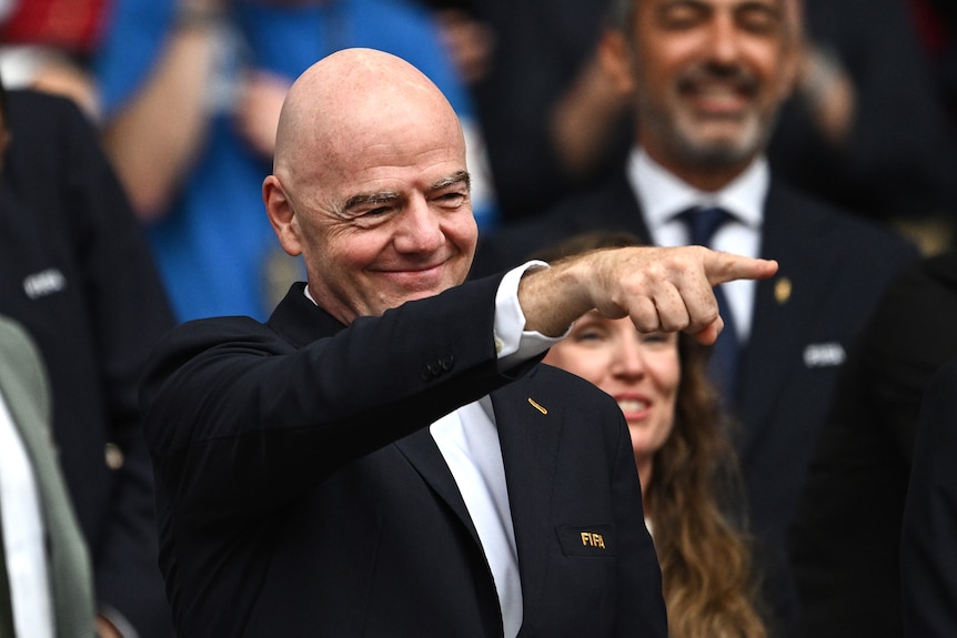 Gianni Infantino smiles and points with his right hand