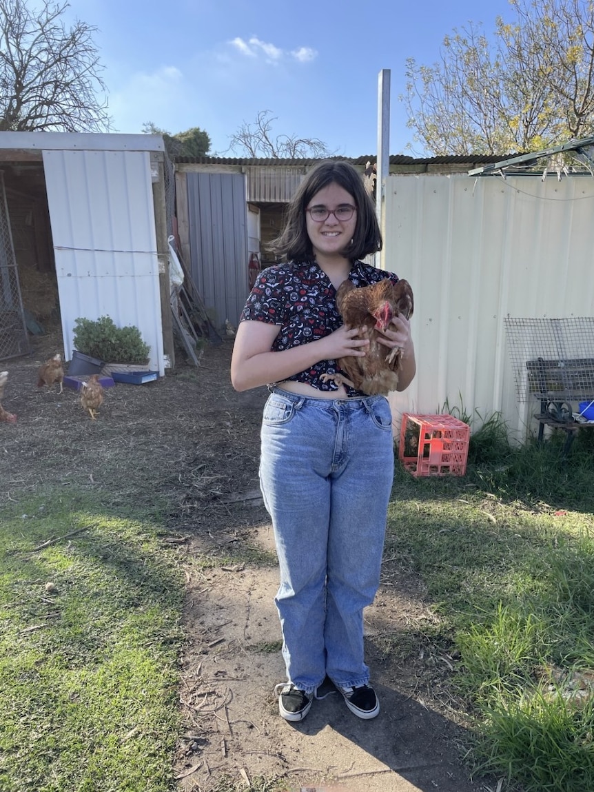 Girl in backyard holding a pet chicken.