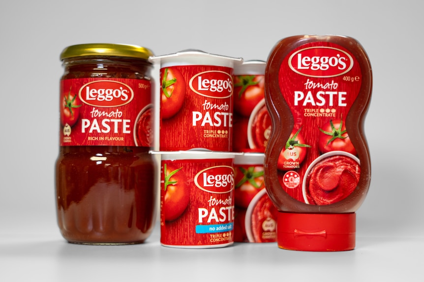 A jar, tubs, and a bottle of Leggo's tomato paste sitting in front of a white background.