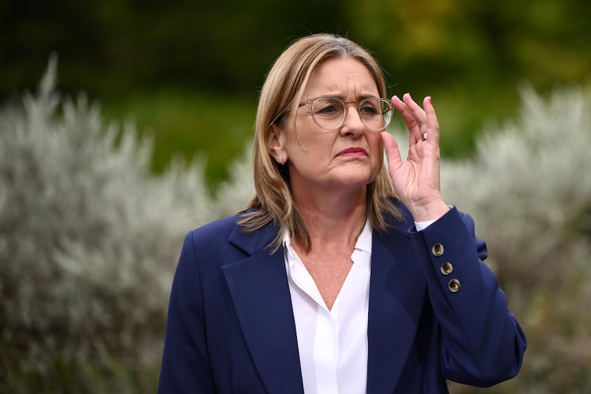 Victorian Premier Jacinta Allan touches her glasses while at a press conference.