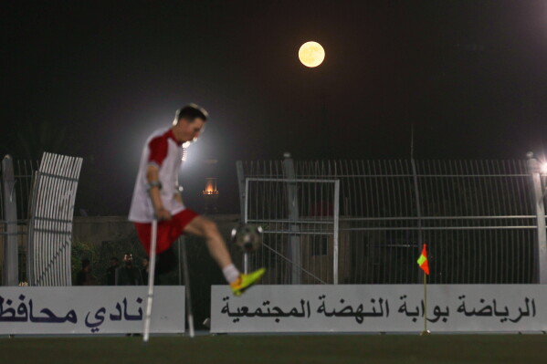 The full moon rises above a player during the final of Syria's first football tournament for people with disabilities at Al-Muhafaza Stadium in Damascus, Syria, Wednesday, July 29, 2026. (AP Photo/Ghaith Alsayed)