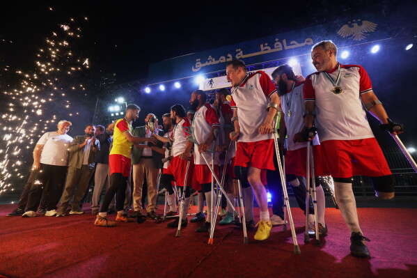 Players from Damascus Governorate Club receive the championship trophy after defeating Omayya Club in the final of Syria's first football tournament for people with disabilities at Al-Muhafaza Stadium in Damascus, Syria, Wednesday, July 29, 2026. (AP Photo/Ghaith Alsayed)