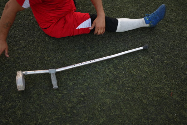 A player stretches beside a crutch before the final of Syria's first football tournament for people with disabilities at Al-Muhafaza Stadium in Damascus, Syria, Wednesday, July 29, 2026. (AP Photo/Ghaith Alsayed)