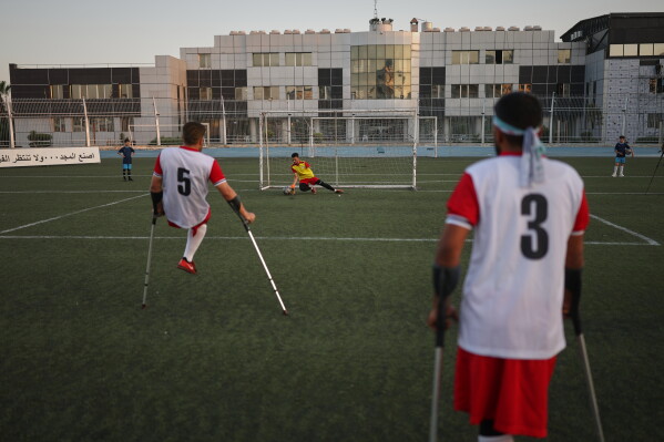 A goalkeeper makes a save as a player takes a shot during warmups before the final of Syria's first football tournament for people with disabilities at Al-Muhafaza Stadium in Damascus, Syria, Wednesday, July 29, 2026. (AP Photo/Ghaith Alsayed)
