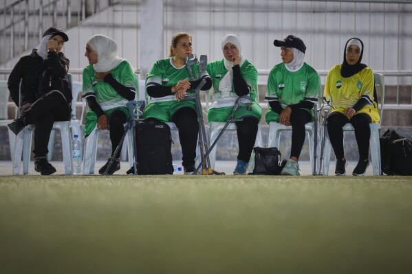 Female players watch the final of Syria's first football tournament for people with disabilities from the sidelines at Al-Muhafaza Stadium in Damascus, Syria, Wednesday, July 29, 2026. (AP Photo/Ghaith Alsayed)