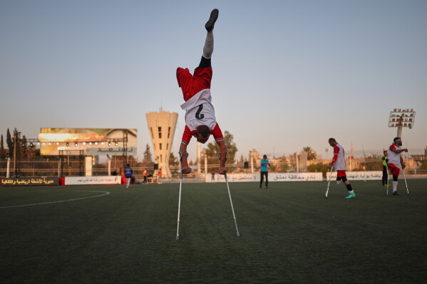 A player balances on his crutches while warming up before the final of Syria's first football tournament for people with disabilities at Al-Muhafaza Stadium in Damascus, Syria, Wednesday, July 29, 2026. (AP Photo/Ghaith Alsayed)