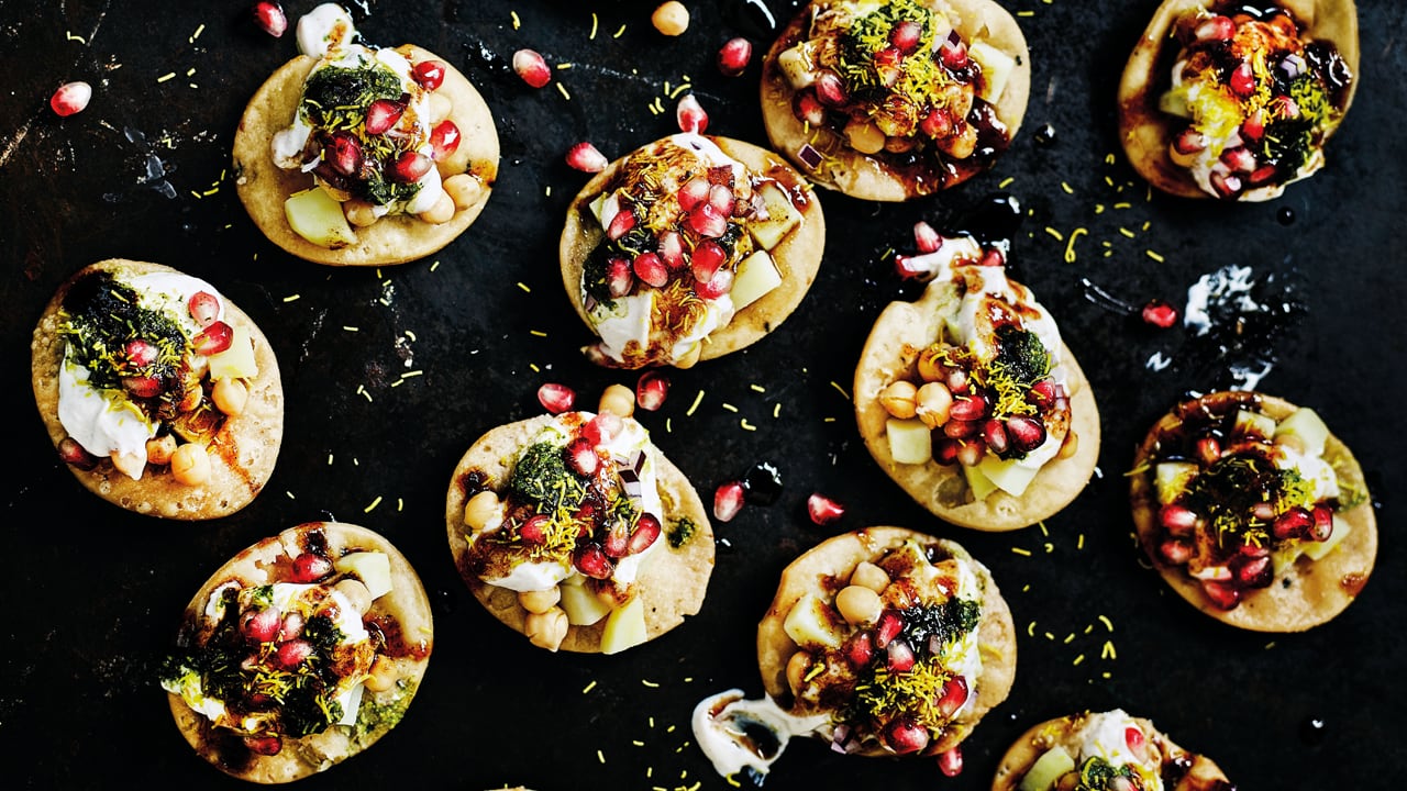 Overhead shot of many papri chaat on a black background. 