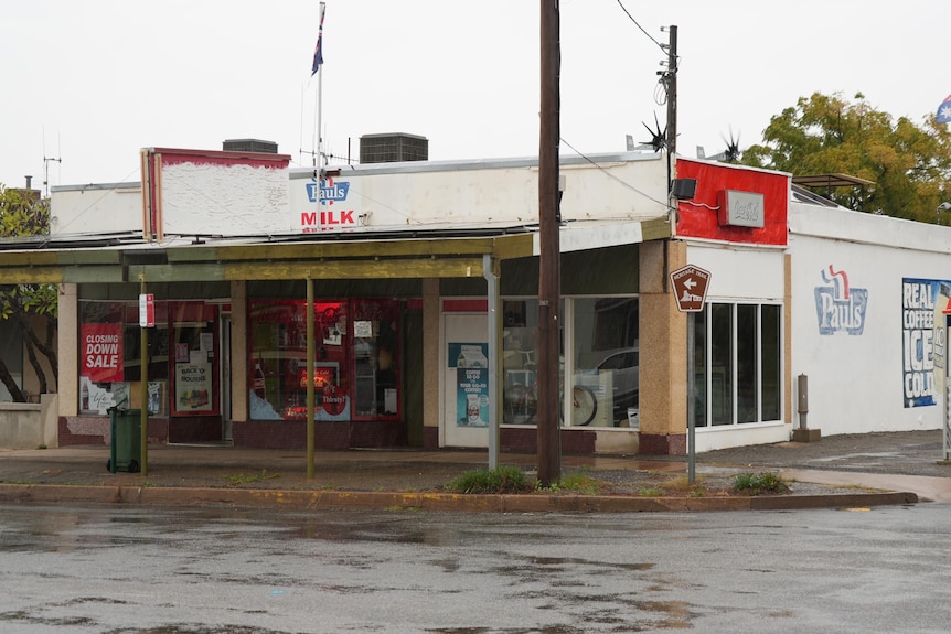 A store on the corner of a wide country road on a drizzly, grey day