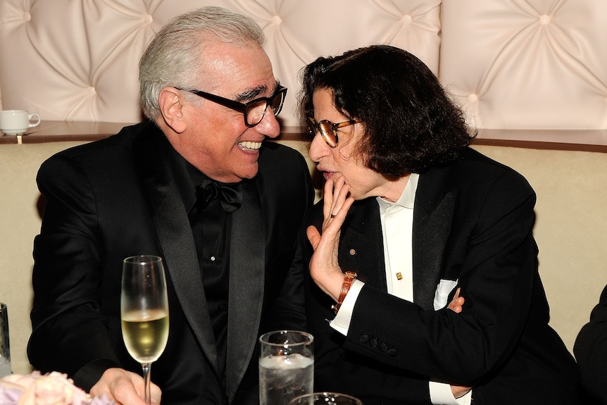 Martin Scorsese and Fran Lebowitz speak intimately at a restaurant table, sharing drinks and laughter.