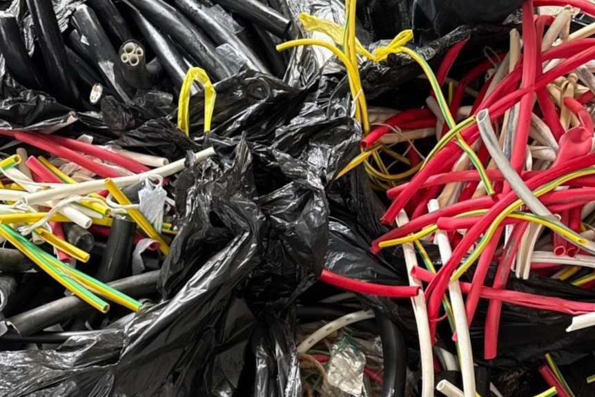 Black plastic garbage bags filled with red, white and yellow cables.