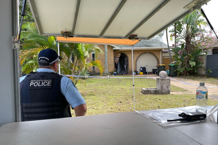 Police officer standing outside the home where a body was discovered in Tweed Heads