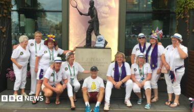 Geoff Hughes is sitting in the middle of a photo in front of a Fred Perry statue surrounded by members of the Andy Murray fan group The Murraynators