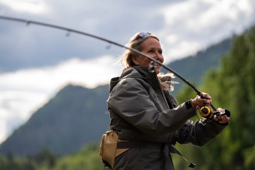 A woman smiles as she fishes