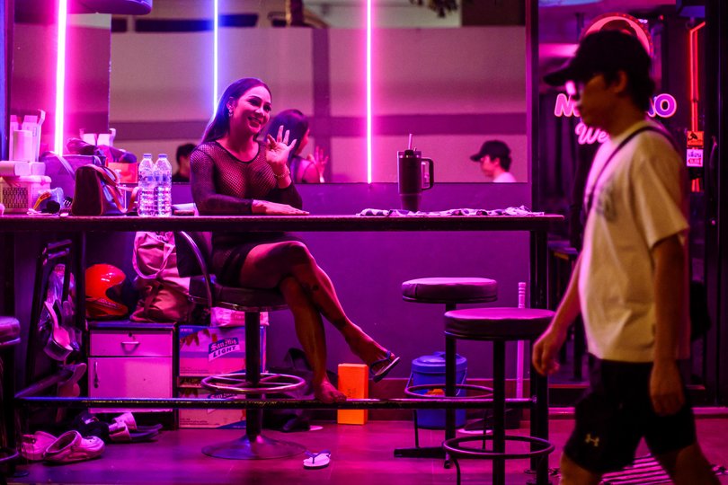 Emily (L), a sex worker, waves as she waits for clients in the back of a bar in Pattaya on July 2, 2026. Scantily dressed and wearing stiletto heels, hundreds of girls, some apparently very young, form a seedy guard of honour under the lights of Soi 6, a street in one of Pattaya's red-light districts. (Photo by ANTHONY WALLACE / AFP) / TO GO WITH: Thailand-Australia-crime-tourism-prostitution Picture: ANTHONY WALLACE