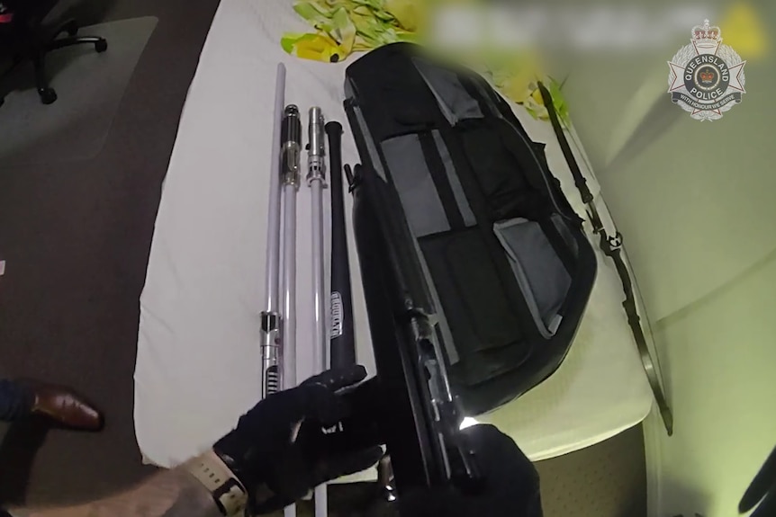 Police bodycam showing guns and tasers on a bed