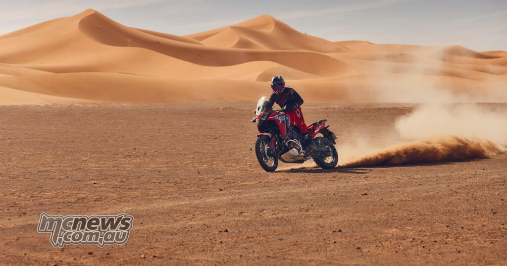 Rider sliding a red 2026 Honda Africa Twin ES DCT across a sandy desert landscape.