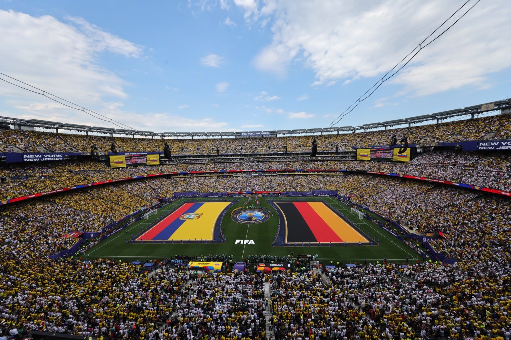 Wide-angle view of a full soccer stadium with large flags of Ecuador and Germany on the field during the 2026 FIFA World Cup match.