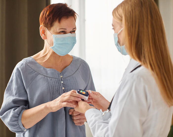 A doctor checks a patient's oxygen with a pulse oximeter, representing aspects of the medical industry.