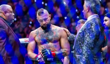 Conor McGregor is consoled by Bruce Buffer in the octagon receiving an injured leg after a quic ...