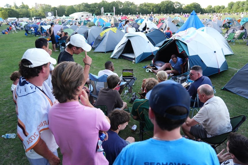A tennis crowd, some watching on laptops