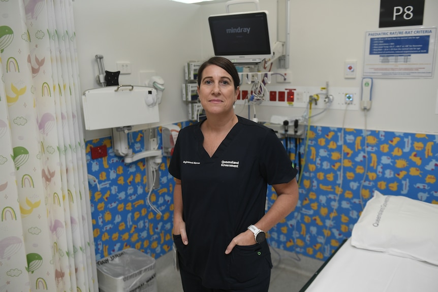 A woman in scrubs stands in a hospital ward