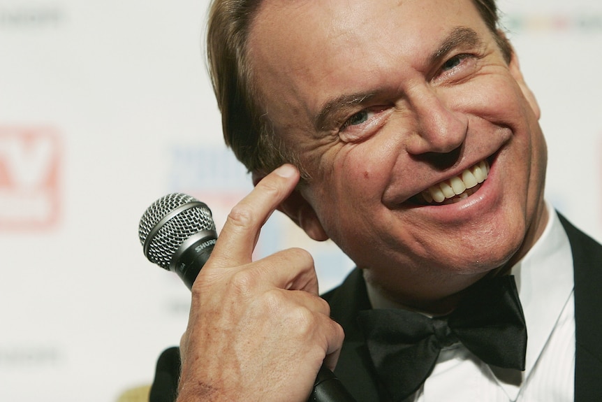 Close up smiling Sam Neill holding microphone 2005