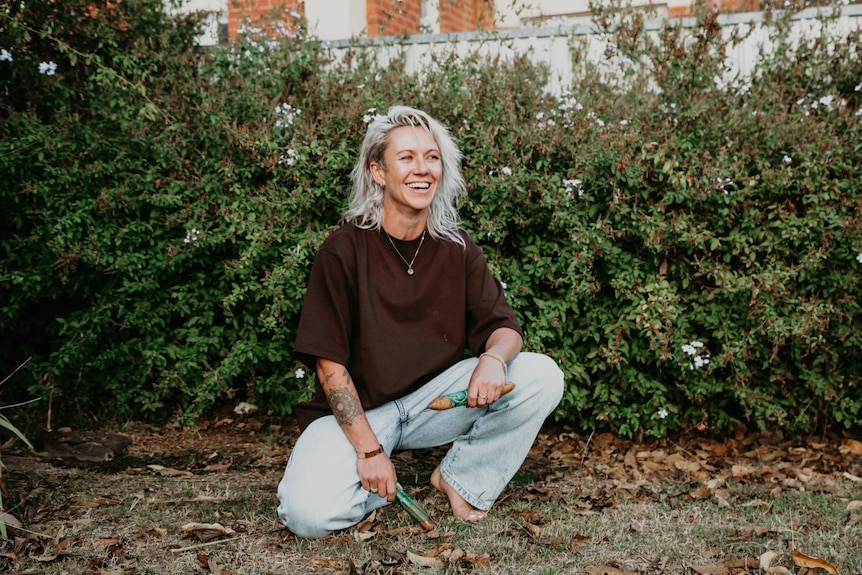Charlie, woman with blonde hair kneeling down smiling off camera.