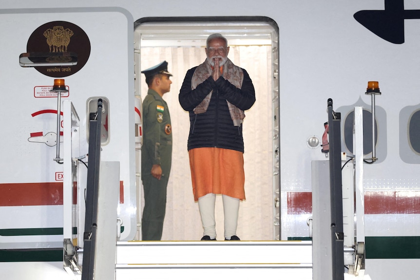 A man stands in the doorway of an airplane.