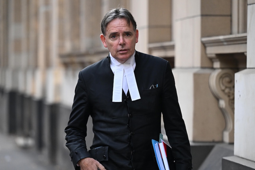 Dermot Dan holding books under one arm walking into court.