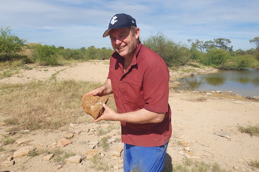 dr matt white standing at the site of the discovery holding a fossil 