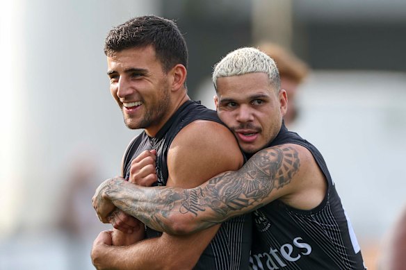 Happier days: Bobby Hill embraces teammate Nick Daicos during a Collingwood training session.