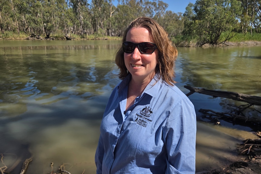Natalie stands by the river and smiles at the camera