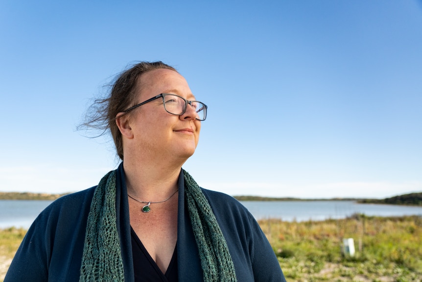 A woman in glasses looking away in the distance.