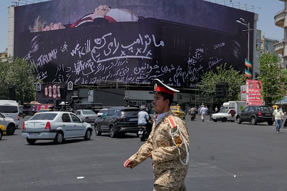 An army cadet walks past a billboard bearing anti-Trump messages, including the phrase “We Kill Trump”, in central Tehran.