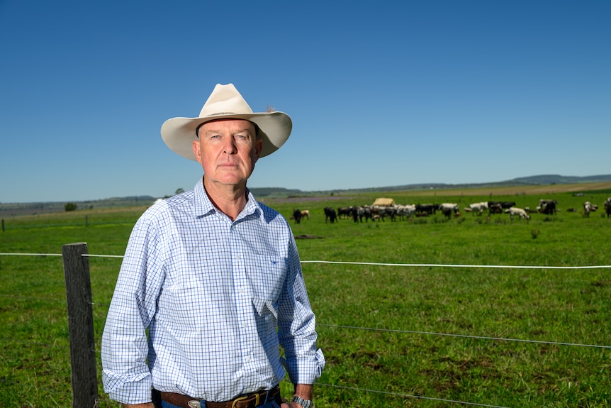 a farmer stands in a green paddock