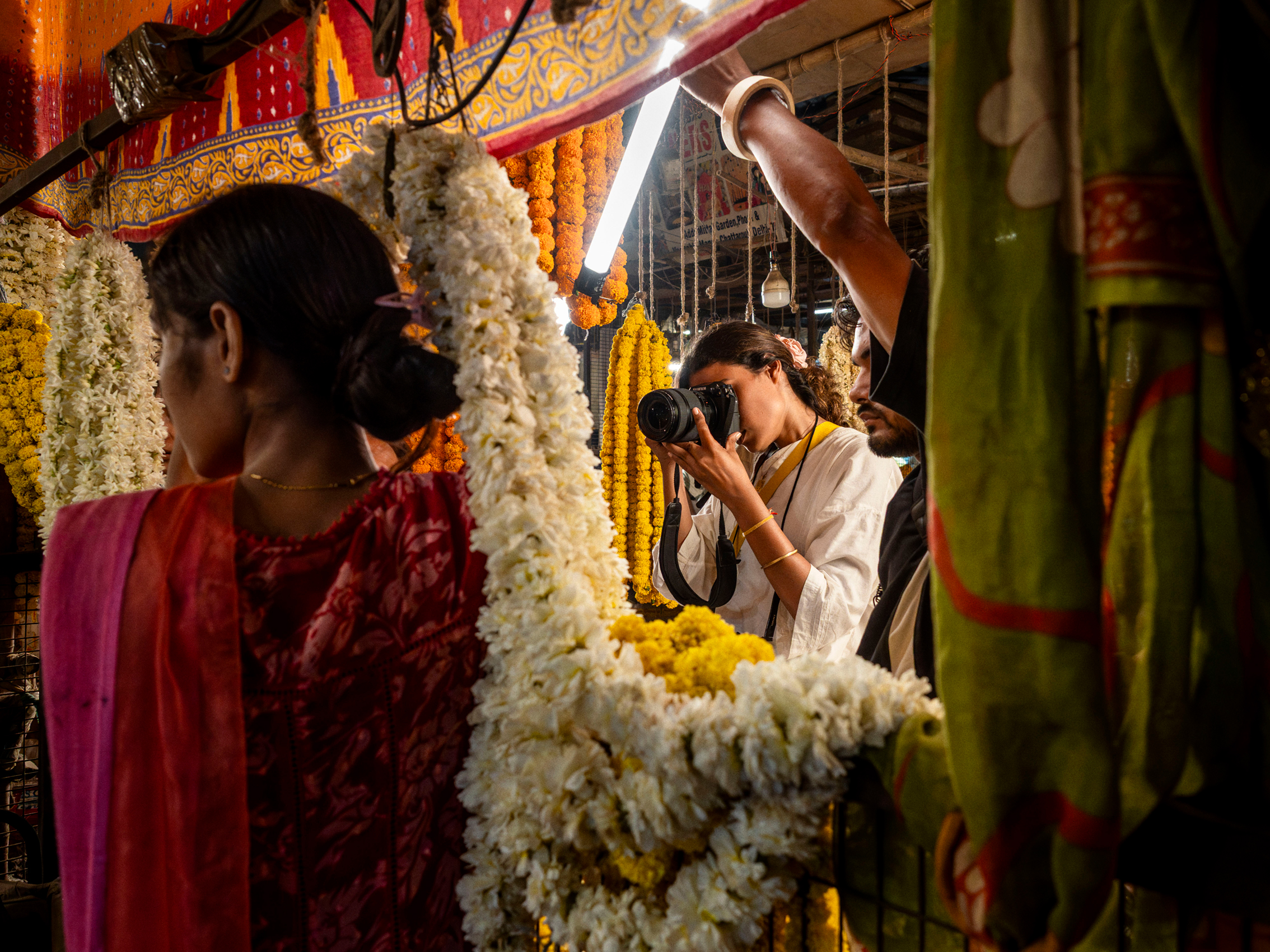 A female photographer is capturing a female model between traditional flower decoration from India