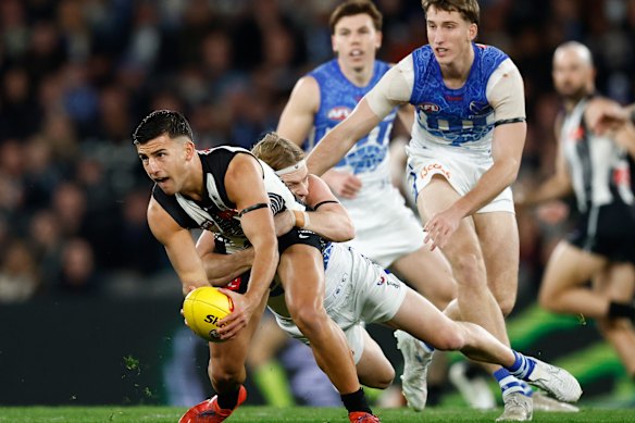 Nick Daicos of the Magpies is tackled by Charlie Spargo of the Kangaroos.
