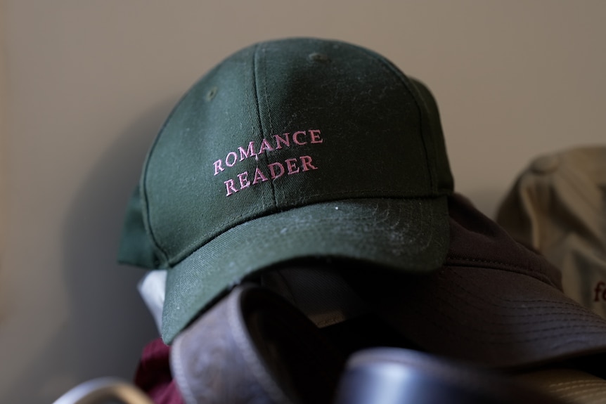 A green cap with the words "romance reader".