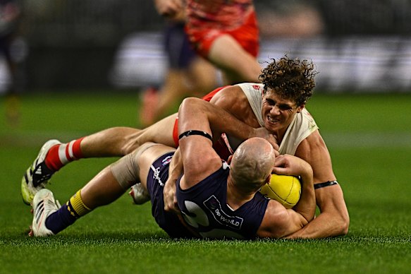 Brennan Cox of the Dockers is tackled by Charlie Curnow