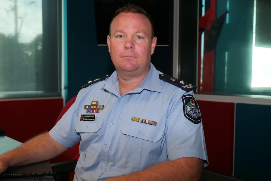 A man in a police uniform, sitting inside a padded room