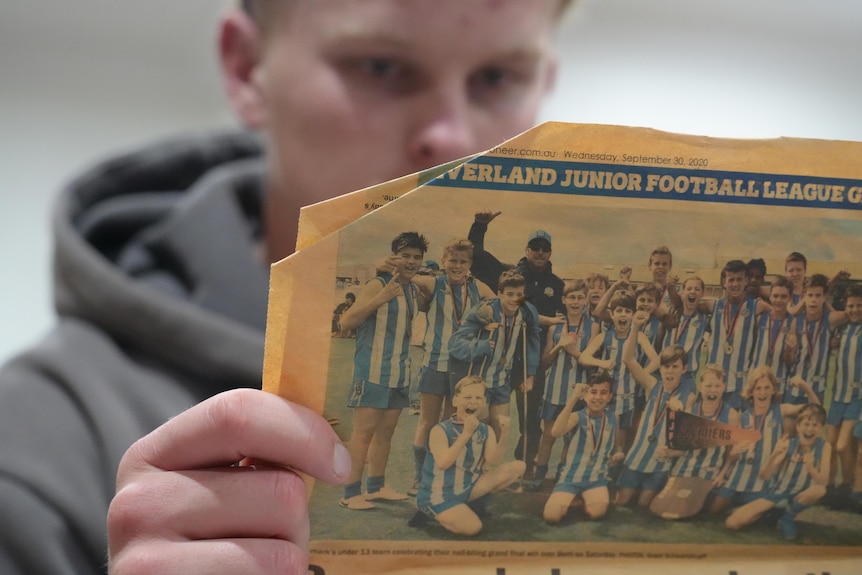 Man holds newspaper clipping.