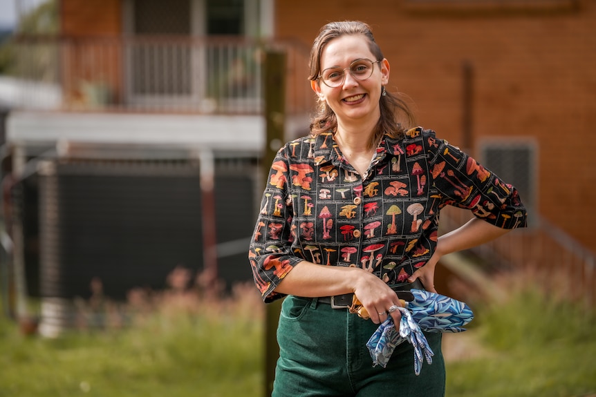 A woman wearing a bright shirt holding gardening gloves