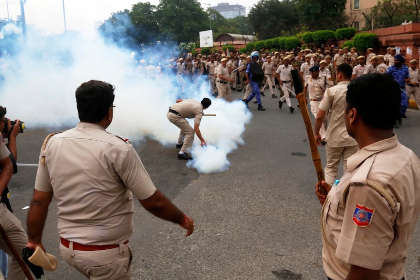 A plume of smoke erupts in the middle of a group of protesters