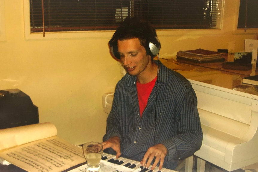 A man wearing headphones is playing the piano.