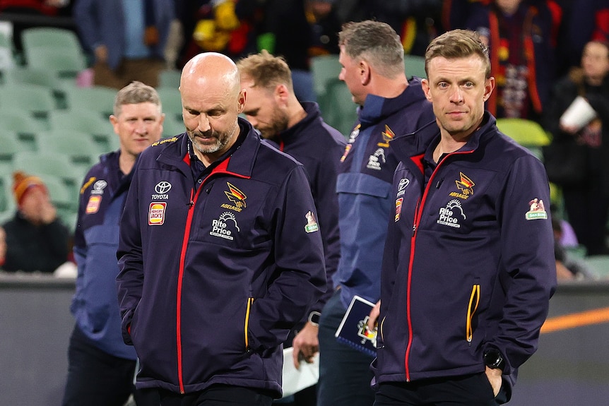 An Adelaide senior AFL coach and his assistant walk off the ground after a loss to Collingwood at Adelaide Oval.