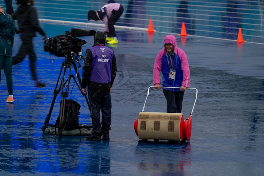 Crews mop up as it rains during the women's high jump final at Scotstoun Stadium.