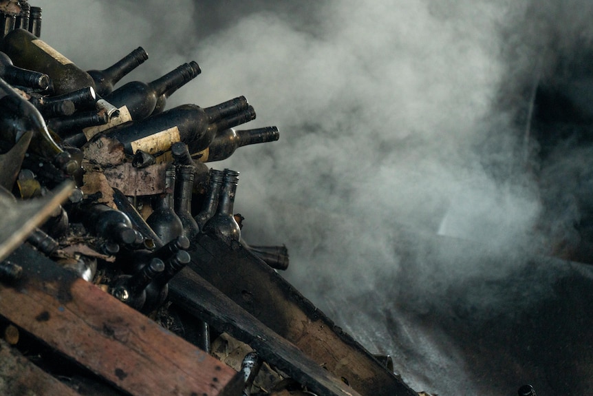 Wine bottles in a pile near smoke haze