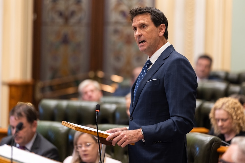 A man in a blue suit speaking in Queensland's state parliament.