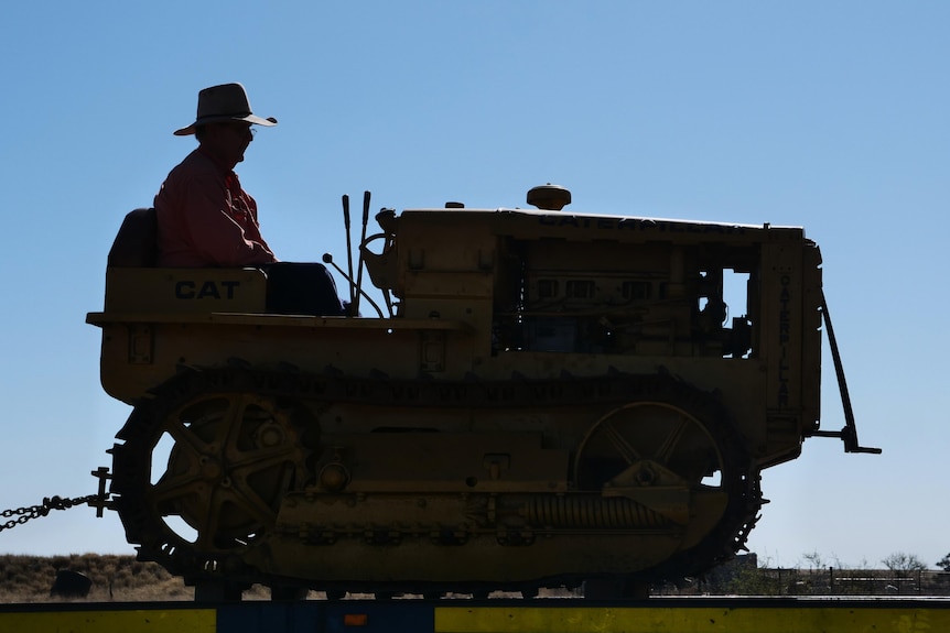 a silhouette of a man sitting on a small tractor